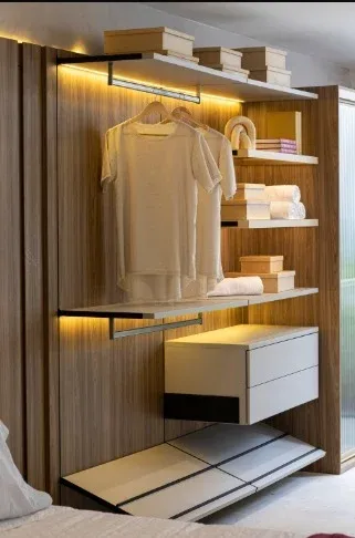 Closet aberto em madeira com araras e luz embutida nas prateleiras