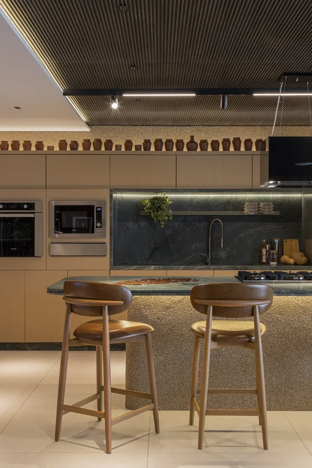 Cozinha gourmet com ilha, banquetas de madeira e forno embutido